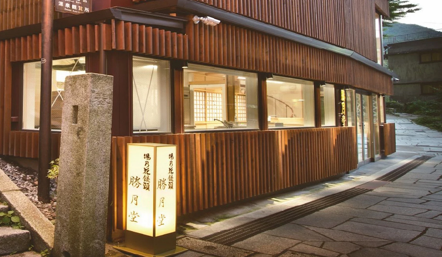 石段街旁木造店鋪勝月堂外觀,暖色燈光照亮日式建築與招牌燈箱